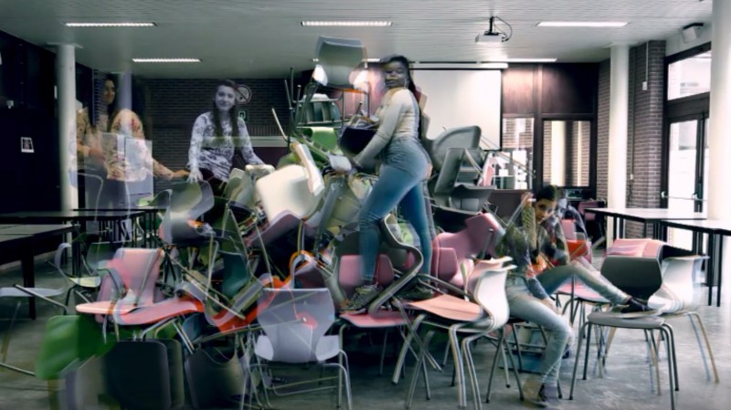 Jongeren poseren op een grote, hoge stapel stoelen in de klas