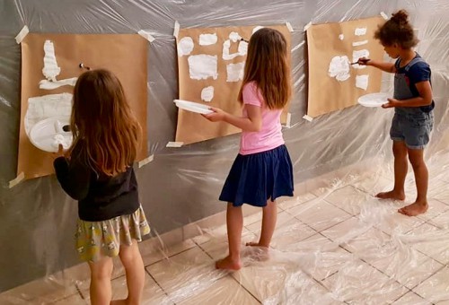 Petites filles peintent sur des grandes feuilles de papier attachés au mur